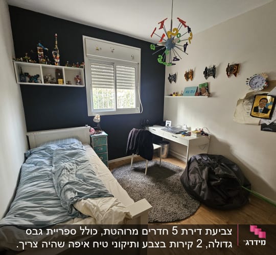 חדר שינה עם מיטה, שולחן עבודה ומדפים עם צעצועים.